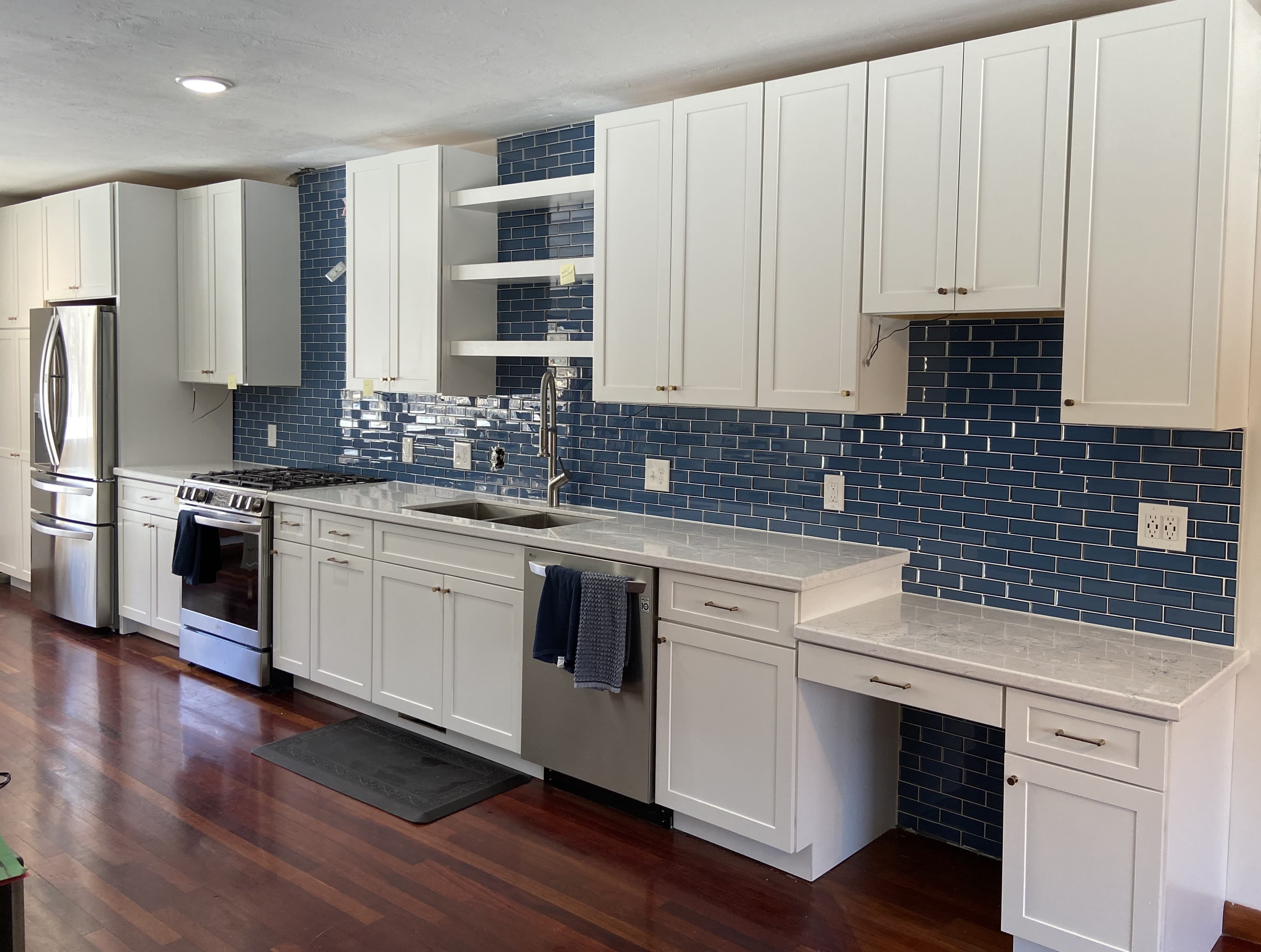 Remodeled kitchen with blue tile backsplash and brown laminate flooring